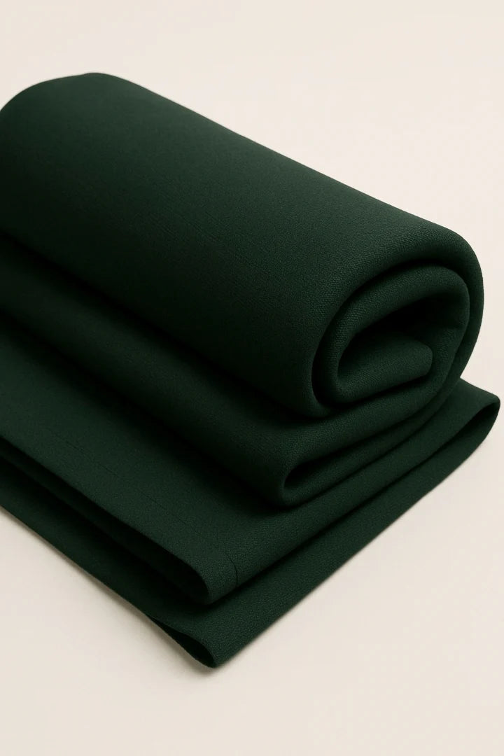 Rolled-up dark green fabric of evergreen shirt crefa on a light beige background